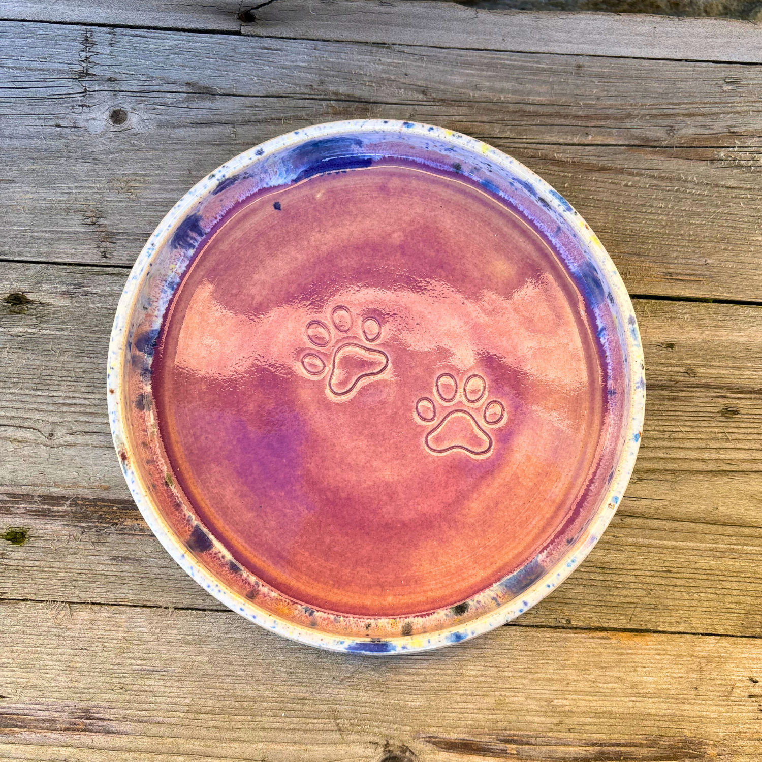 Ceramic bowl with paw prints on a wooden surface