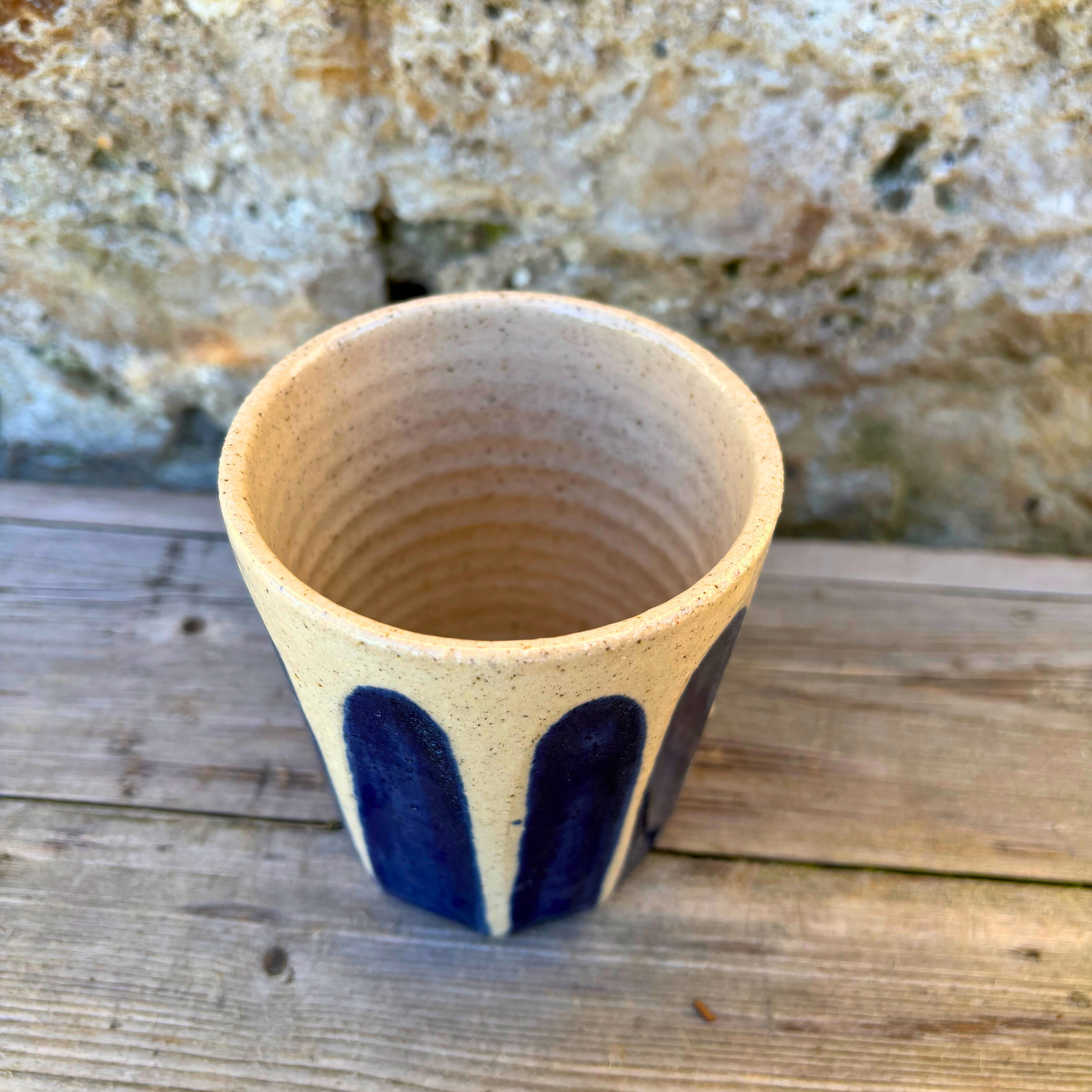 Ceramic cup with blue accents on a wooden surface with a stone background