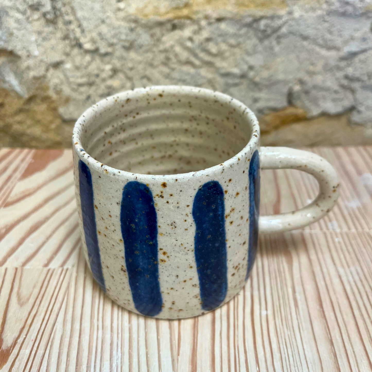Ceramic mug with blue stripes on a wooden surface