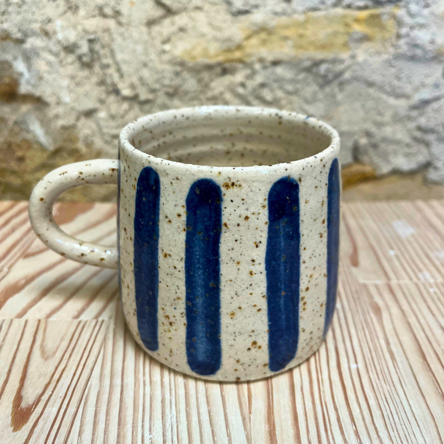 Ceramic mug with blue stripes on a wooden surface
