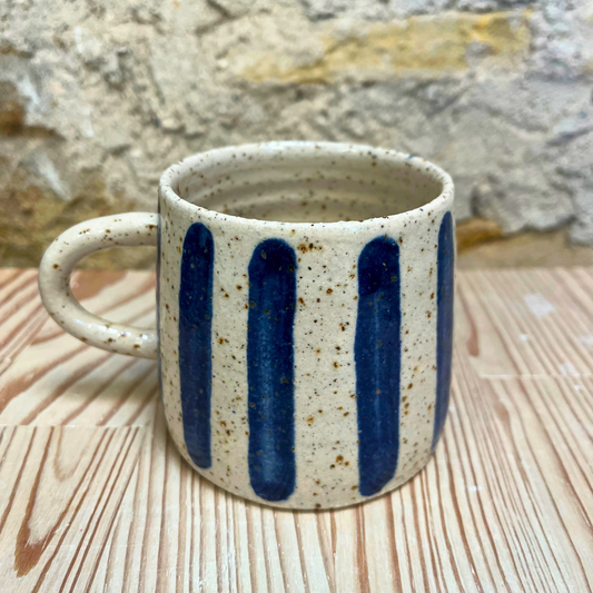 Ceramic mug with blue stripes on a wooden surface