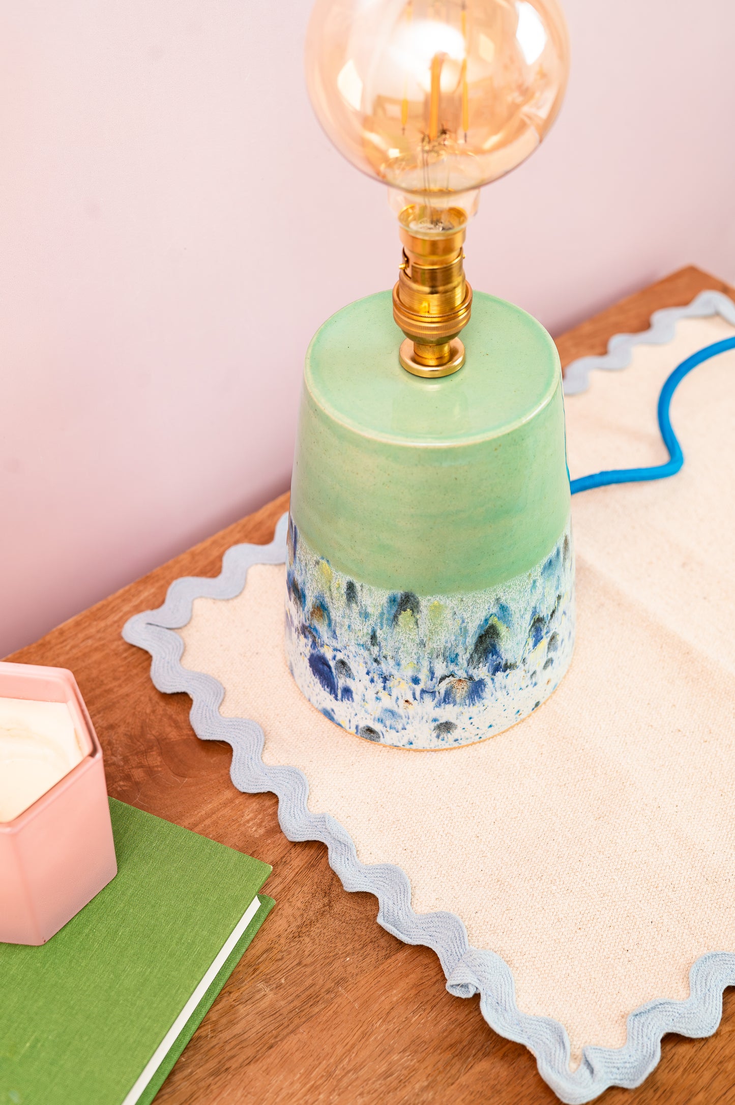 Green ceramic lamp with a decorative base on a wooden surface