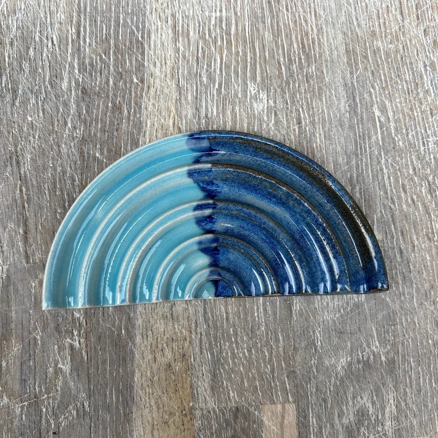 Blue ceramic half-circle dish on a wooden surface