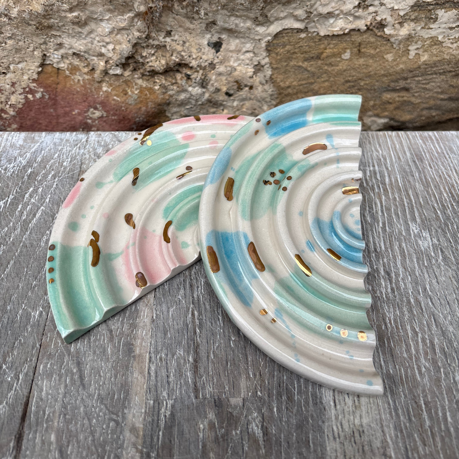 Two ceramic soap dishes with wavy design on a wooden surface