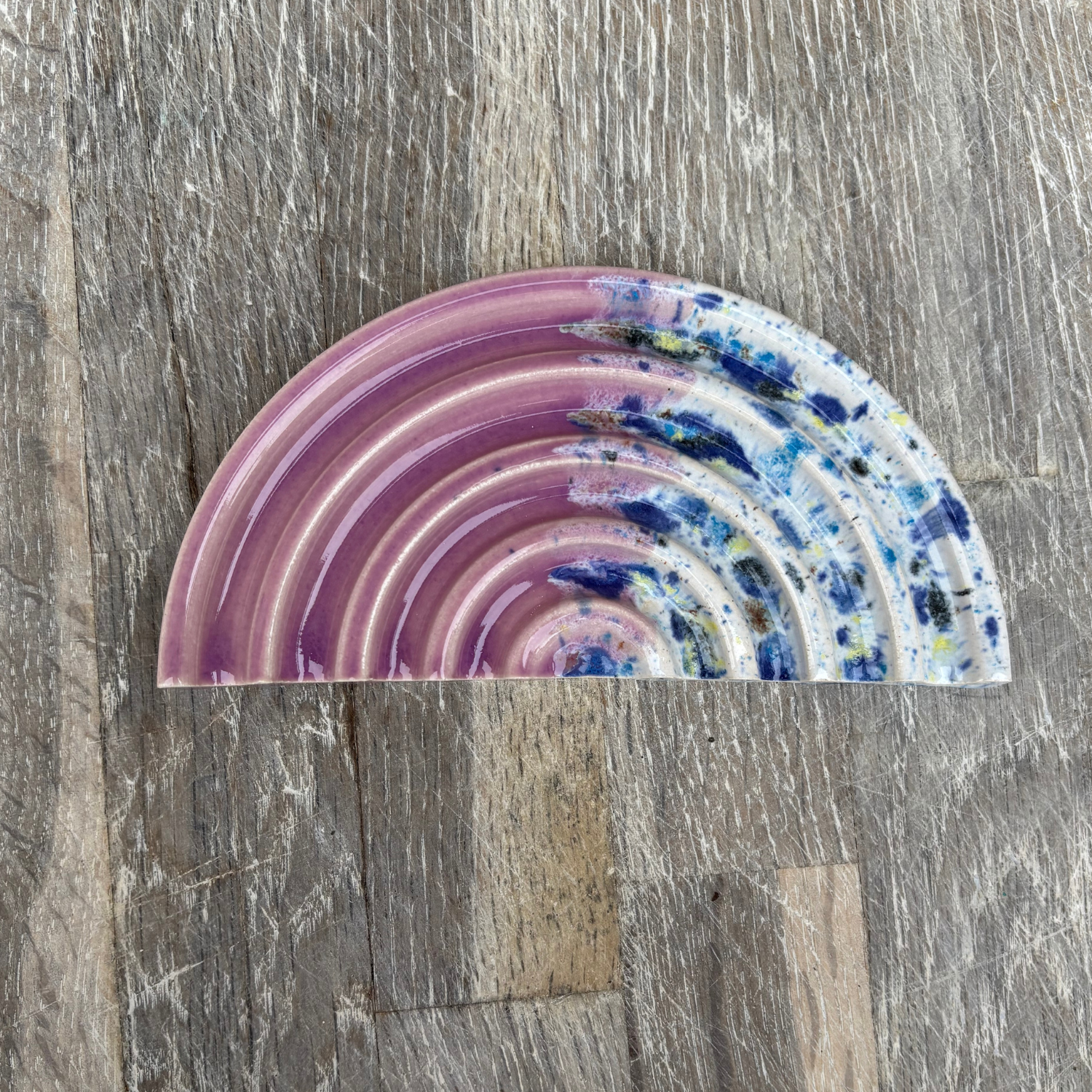 Decorative half-circle soap dish with wavy pattern on a wooden surface
