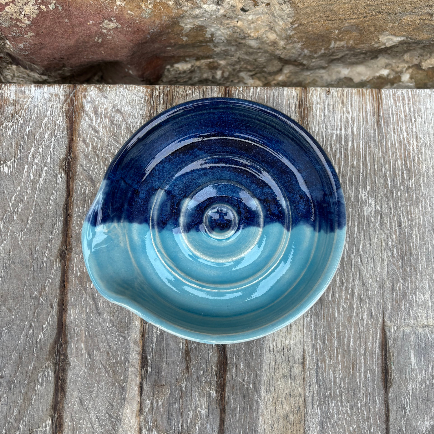 Blue ceramic bowl on a wooden surface with a stone background