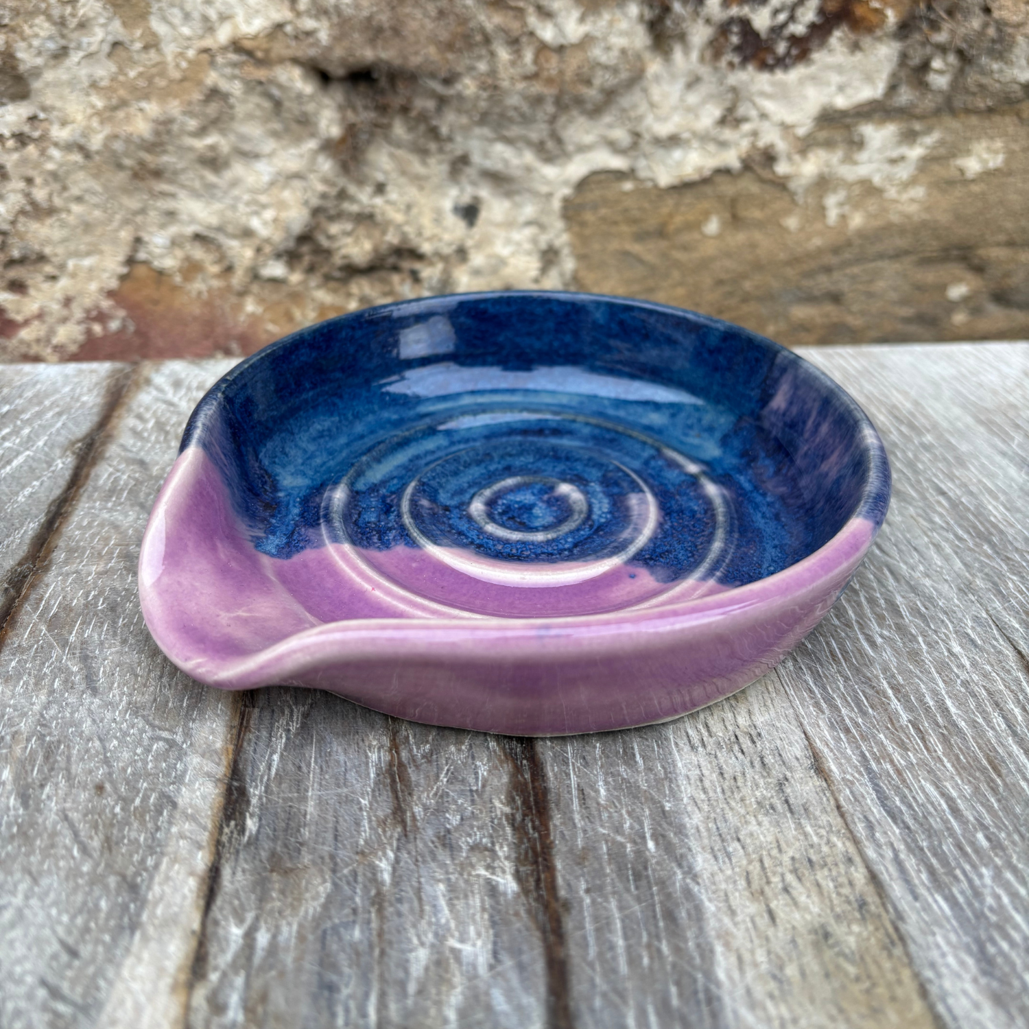 Ceramic dish with blue and purple spiral design on a wooden surface