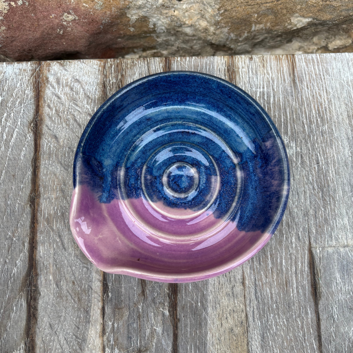Ceramic bowl with blue and purple spiral design on a wooden surface