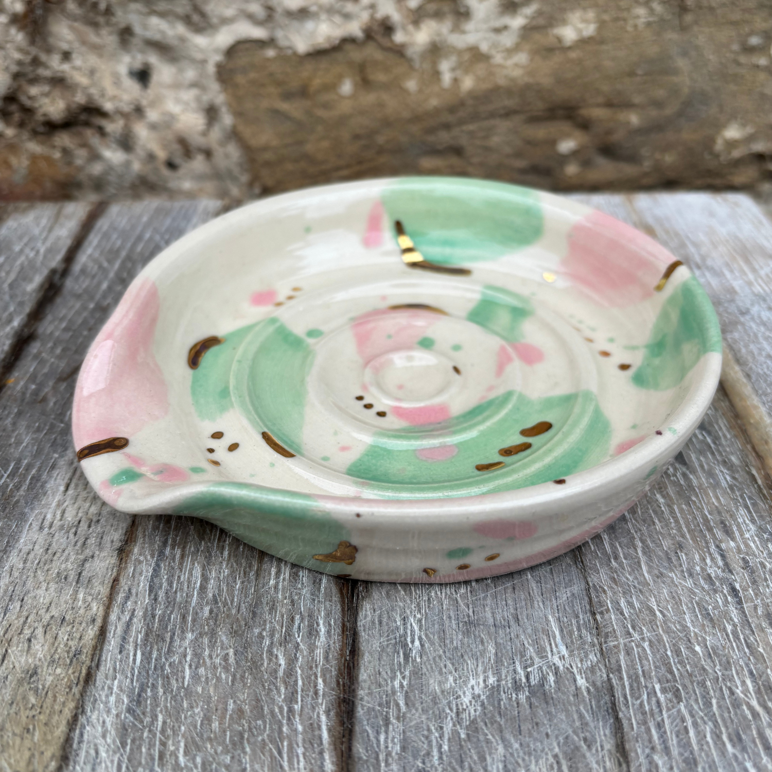 Decorative ceramic dish with pink and green patterns on a wooden surface