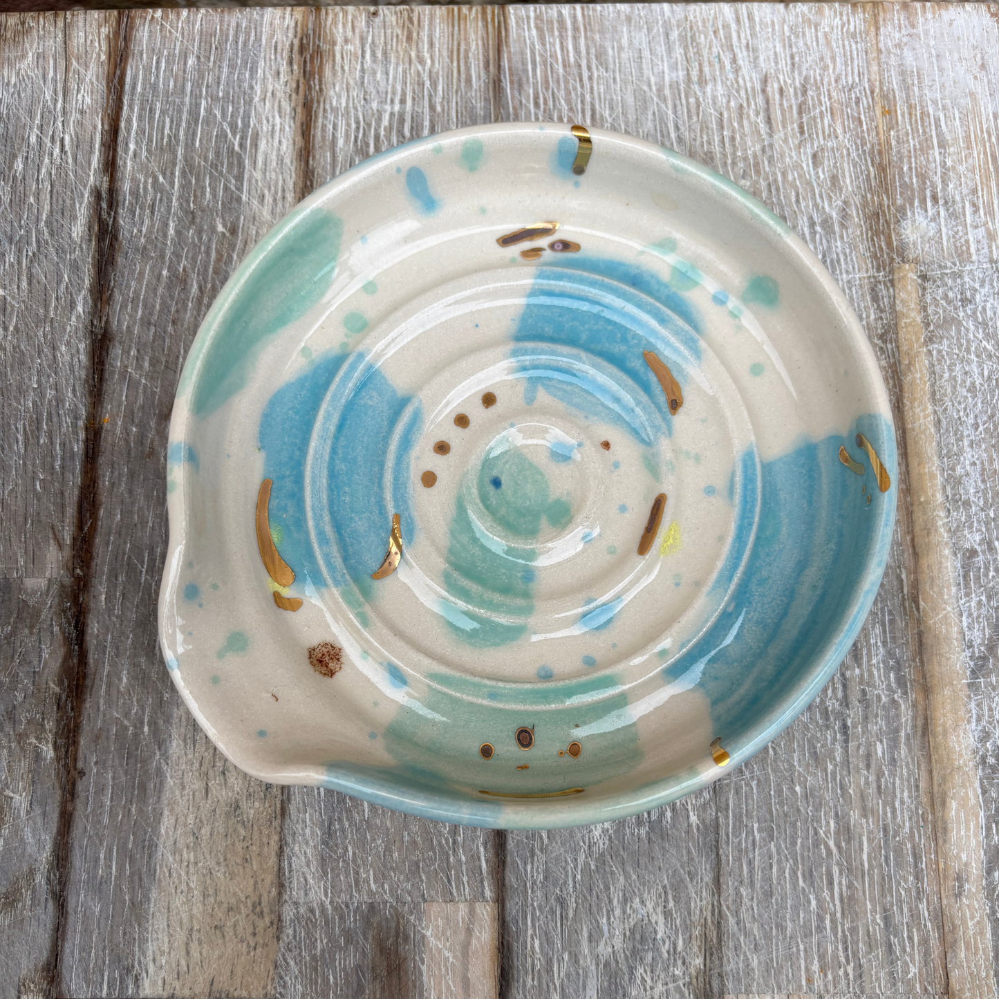 Ceramic dish with blue and green spiral design on a wooden surface