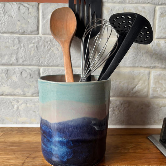 Ceramic utensil holder with kitchen tools against a tiled wall background