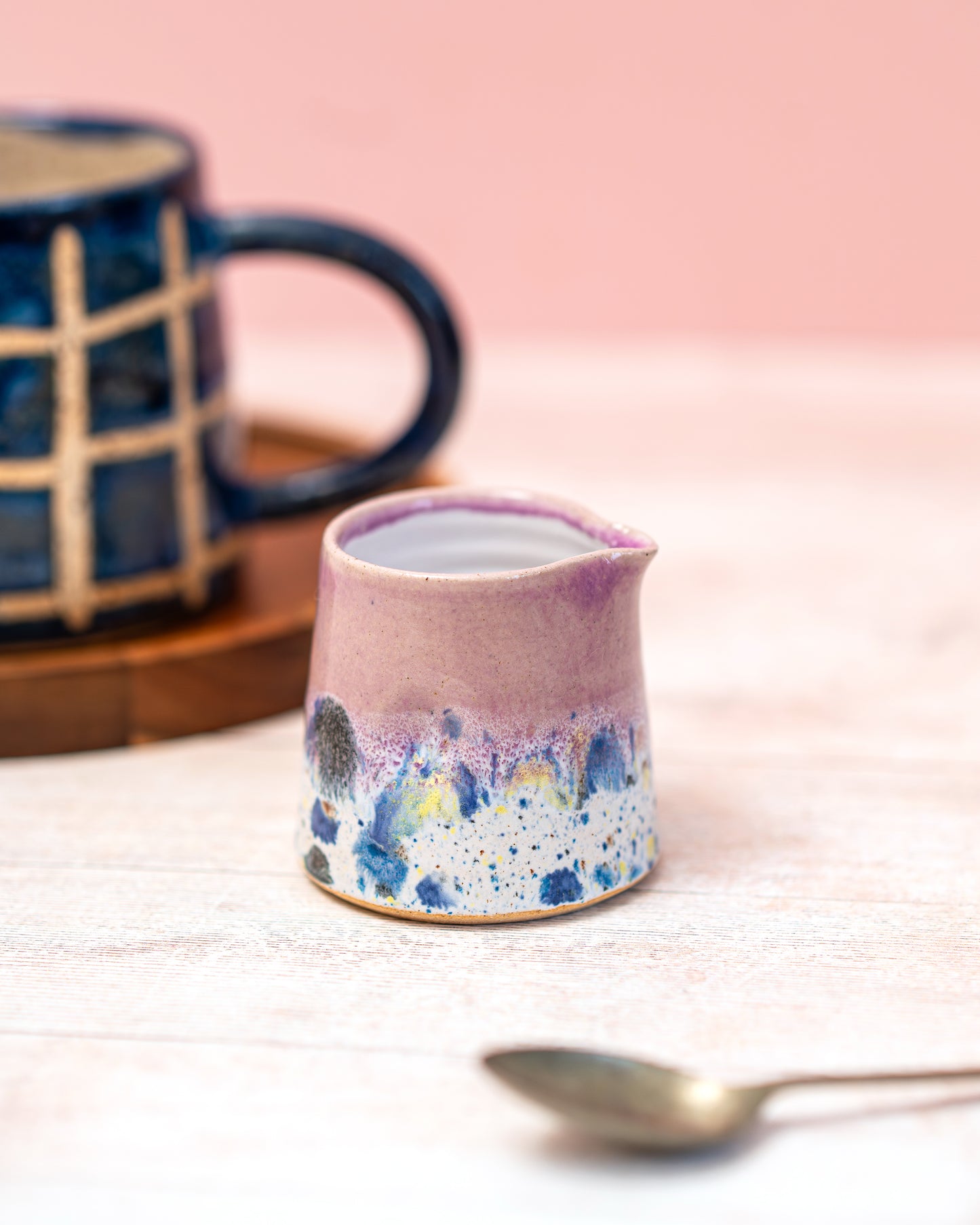 Small ceramic pitcher with floral design on a pink background