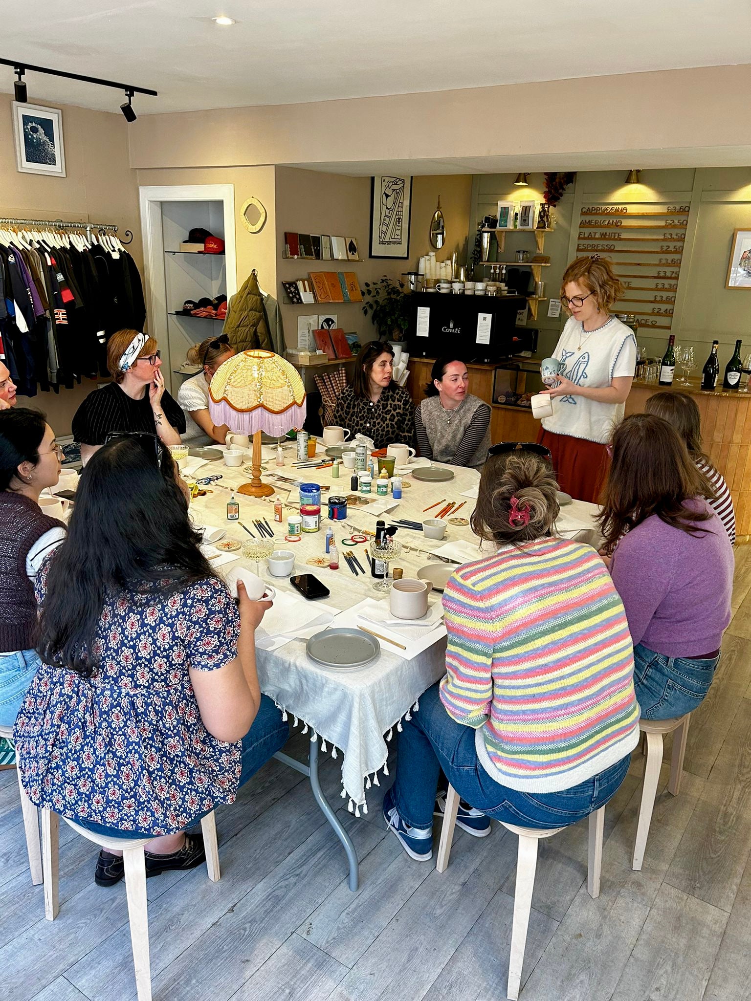 Group of people sitting around a table in a casual setting with various items on it.