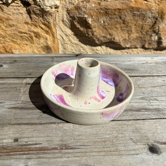 Ceramic candle holder with colorful glaze on a wooden surface
