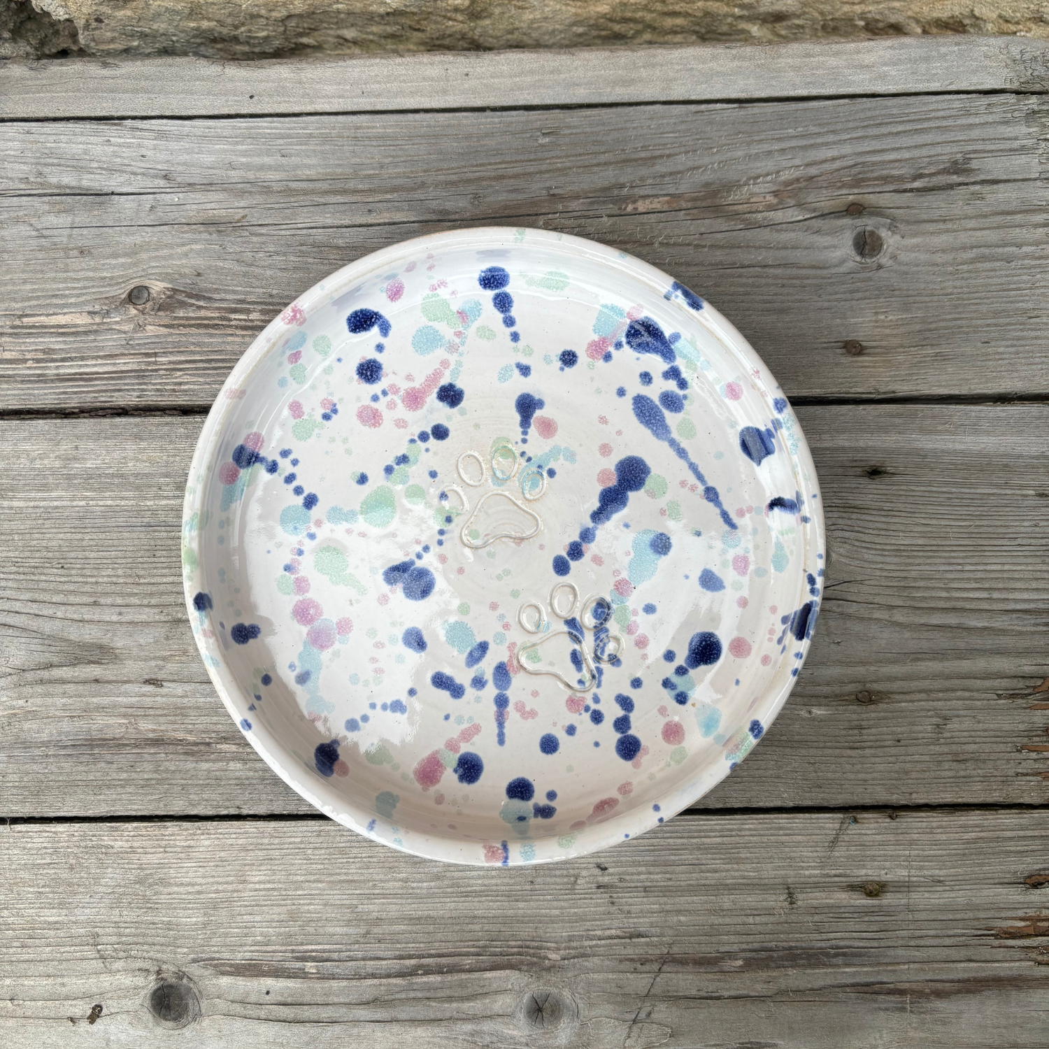 Ceramic plate with colorful splatter design on a wooden surface
