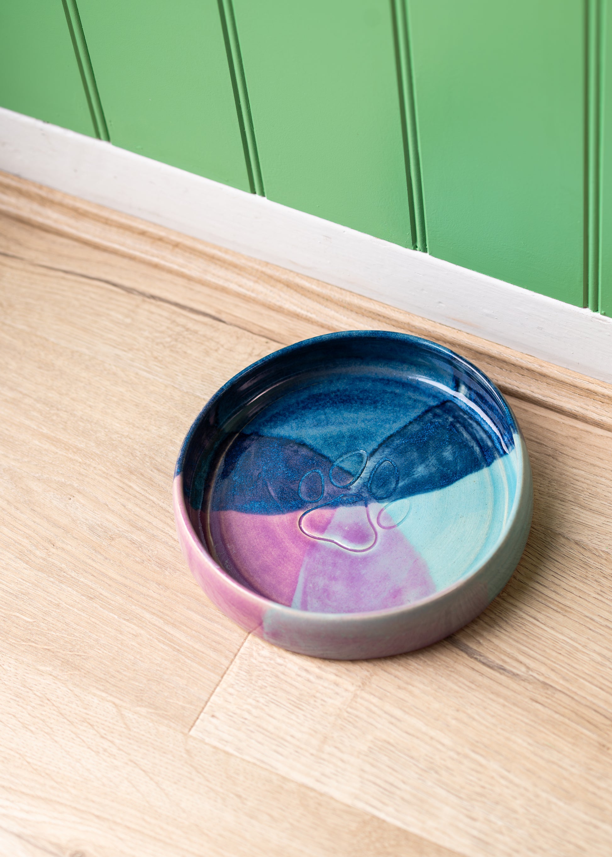 Multicolored ceramic bowl on a wooden surface with a green panel background