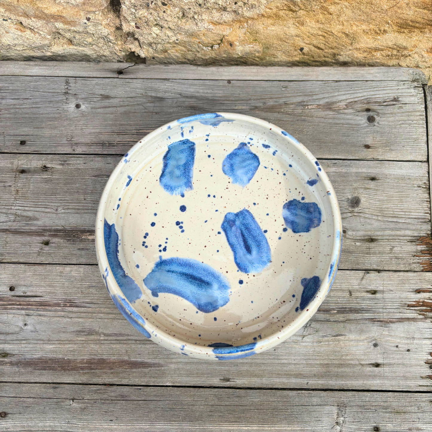 Ceramic bowl with blue speckles on a wooden surface
