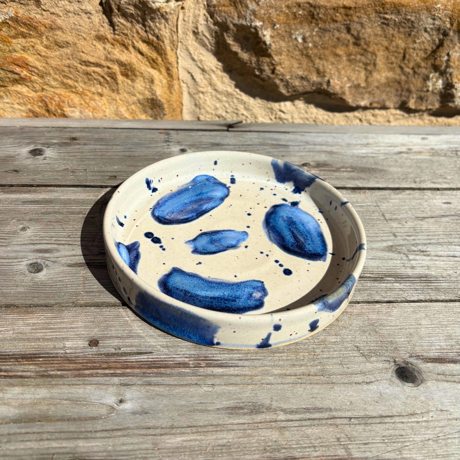 Ceramic trinket dish with blue abstract patterns on a wooden surface