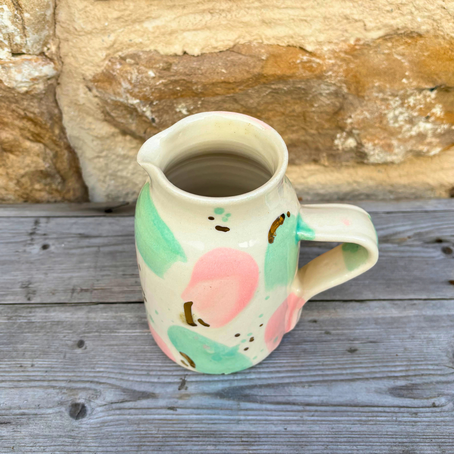 Ceramic pitcher with colorful design on a wooden surface