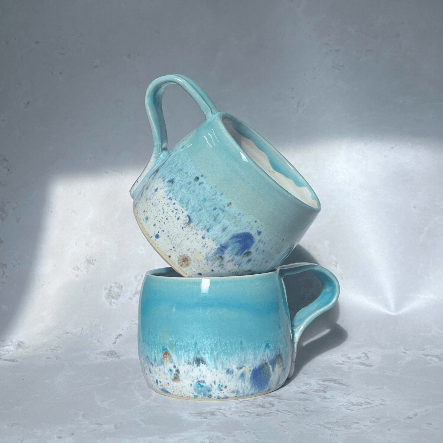 Ella Fletcher Designs Handmade Ceramic Large Round Mugs in Pale Blue Shoreline Design, solid blue with speckled multicolour design on a round handmade mug
