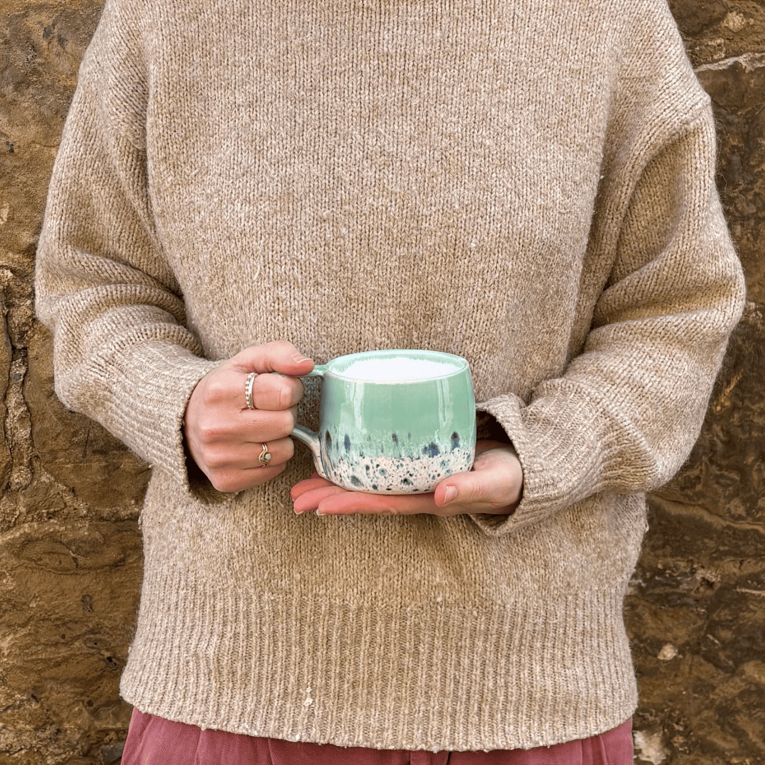 Ella Fletcher Designs Handmade Ceramic Mug in Green Shoreline Design, round mug held with pale green and multicolour speckle design