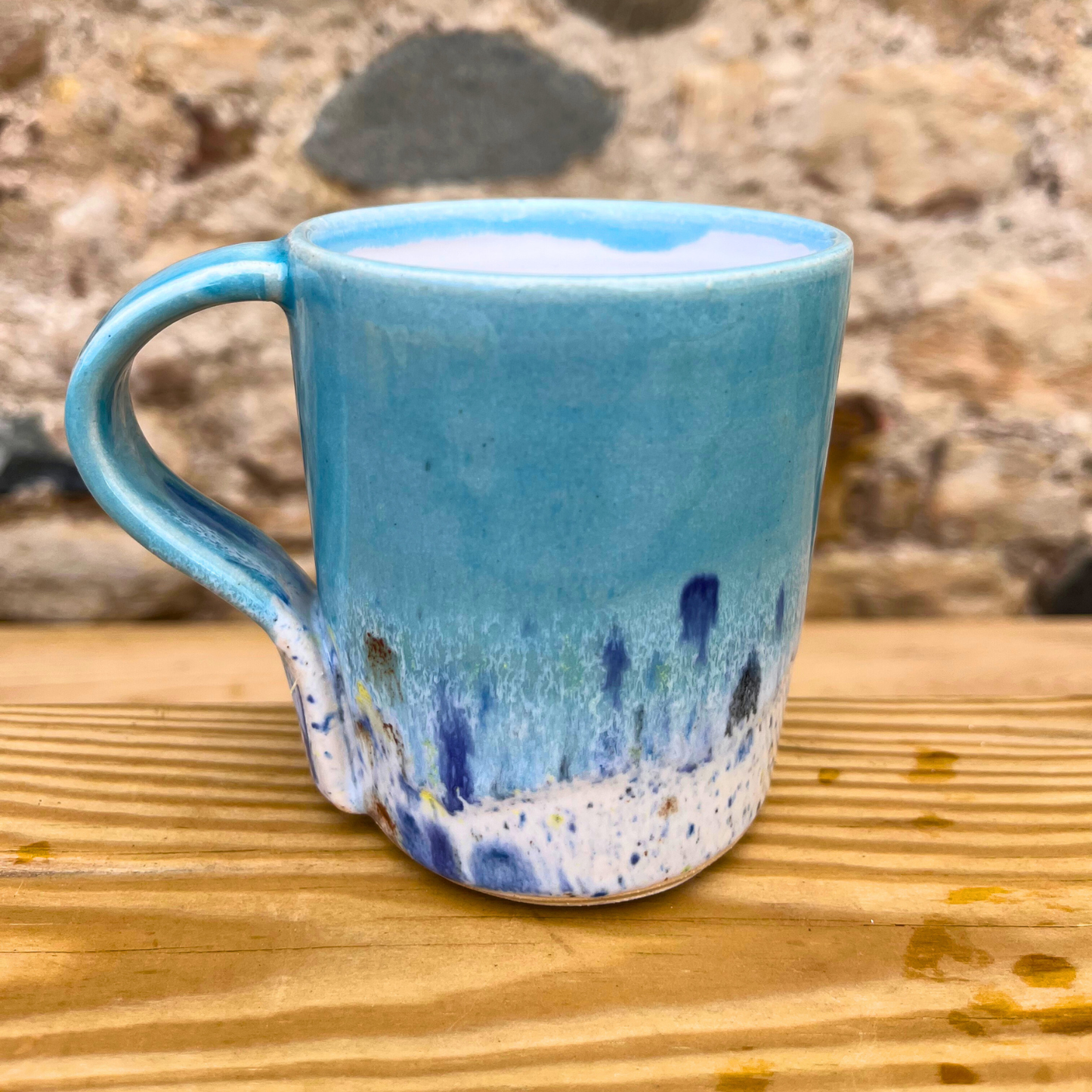 Blue ceramic mug with speckled design on a wooden surface