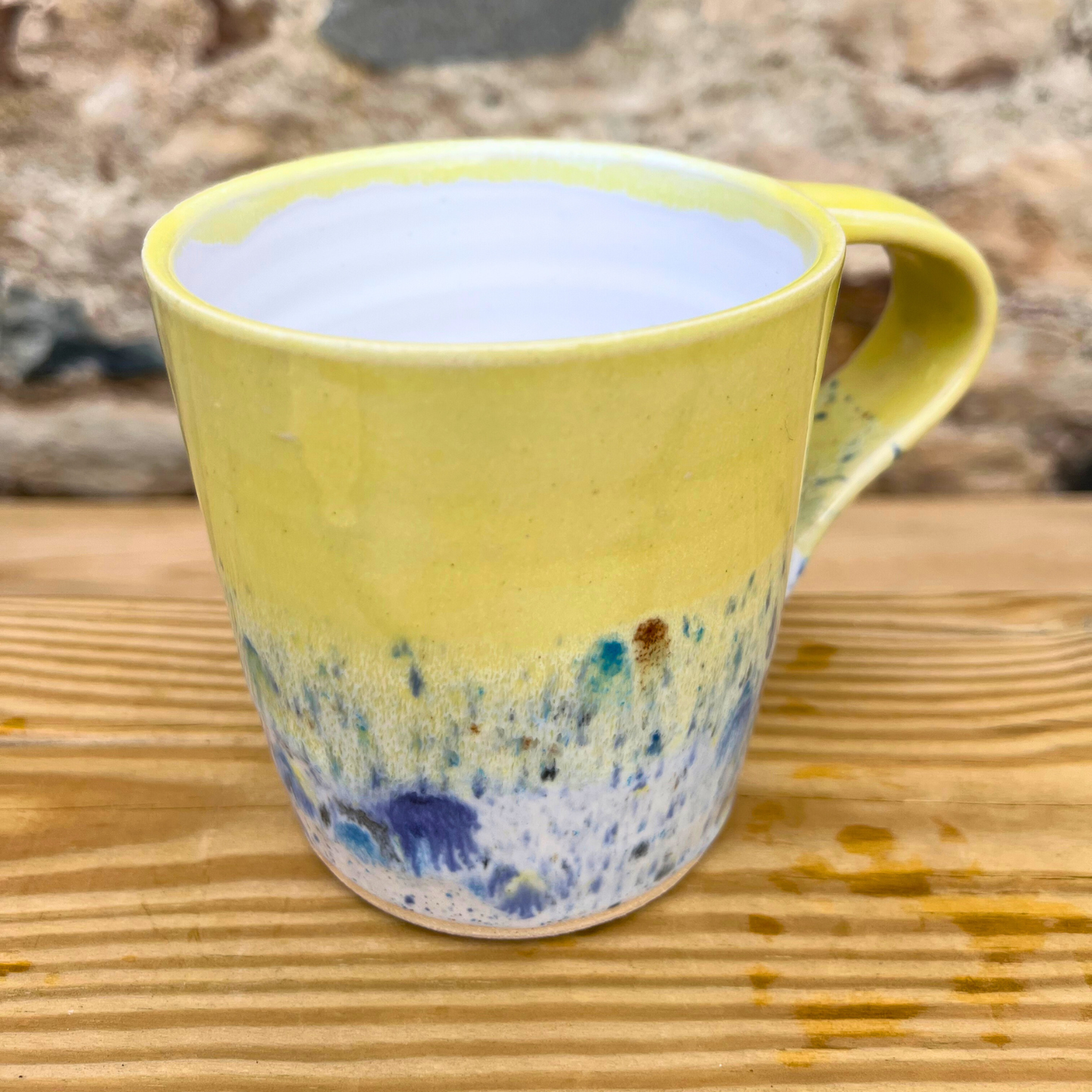 Yellow mug with a speckled design on a wooden surface