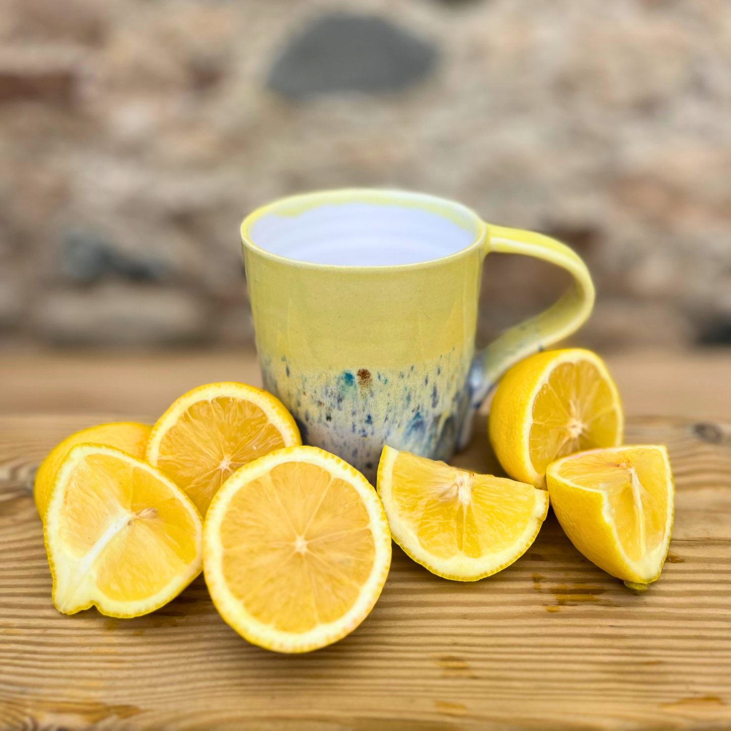 Yellow mug surrounded by sliced lemons on a wooden surface