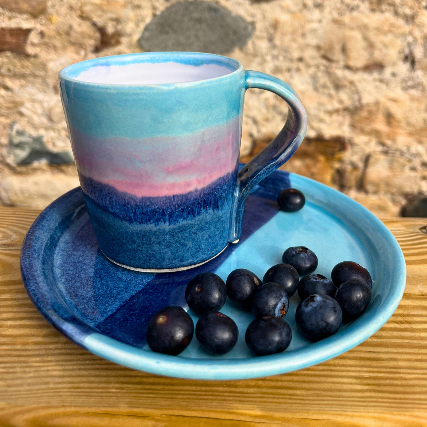 Blue ceramic cup and saucer with plums on a wooden surface