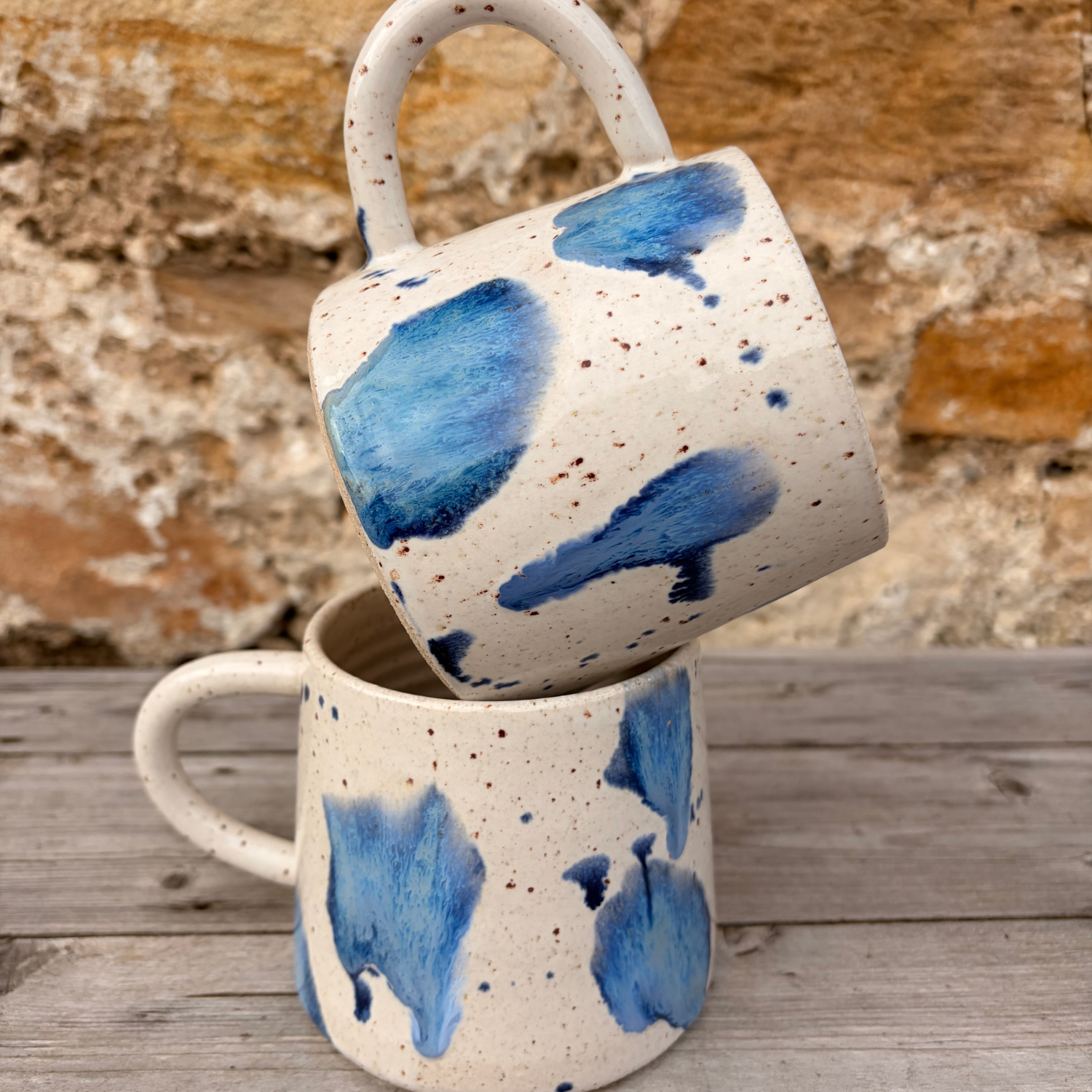 Two ceramic mugs with blue abstract patterns on a wooden surface.