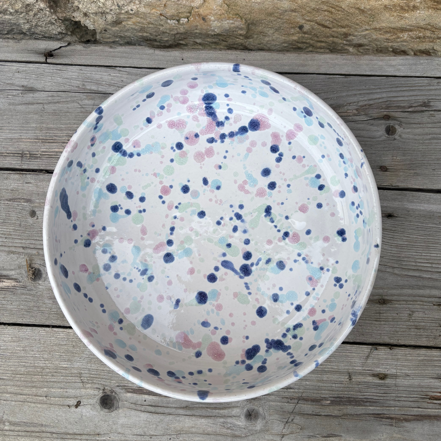 White bowl with blue and pink speckles on a wooden surface