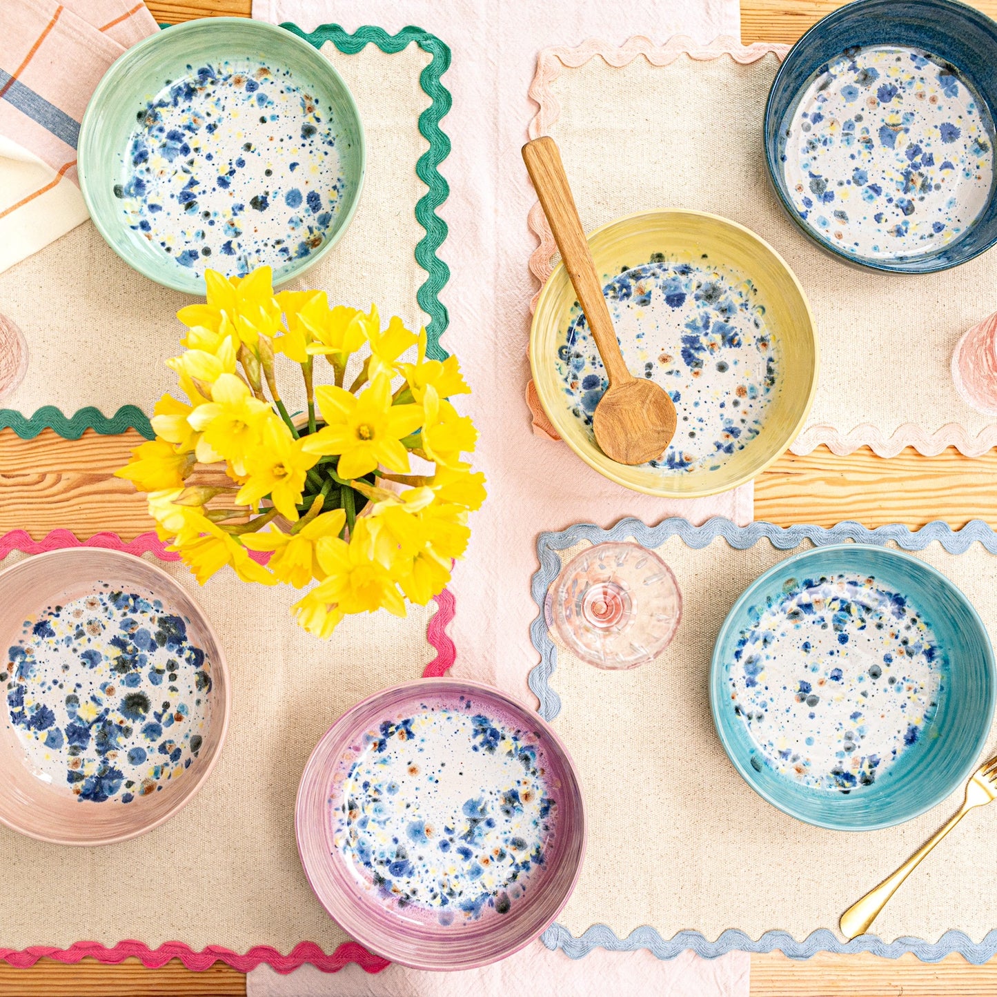 Ella Fletcher Designs Handmade Ceramic Pasta Bowls, table spread featuring the colour range of the shoreline design, solid outside with multicoloured speckles inside, pink, green, yellow, blue and navy