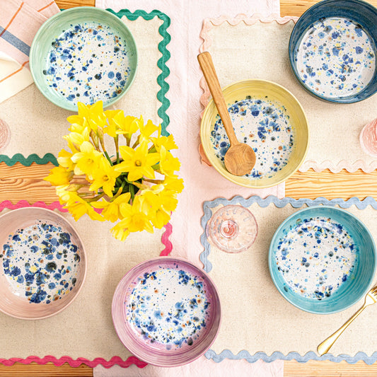 Ella Fletcher Designs Handmade Ceramic Pasta Bowls, table spread featuring the colour range of the shoreline design, solid outside with multicoloured speckles inside, pink, green, yellow, blue and navy