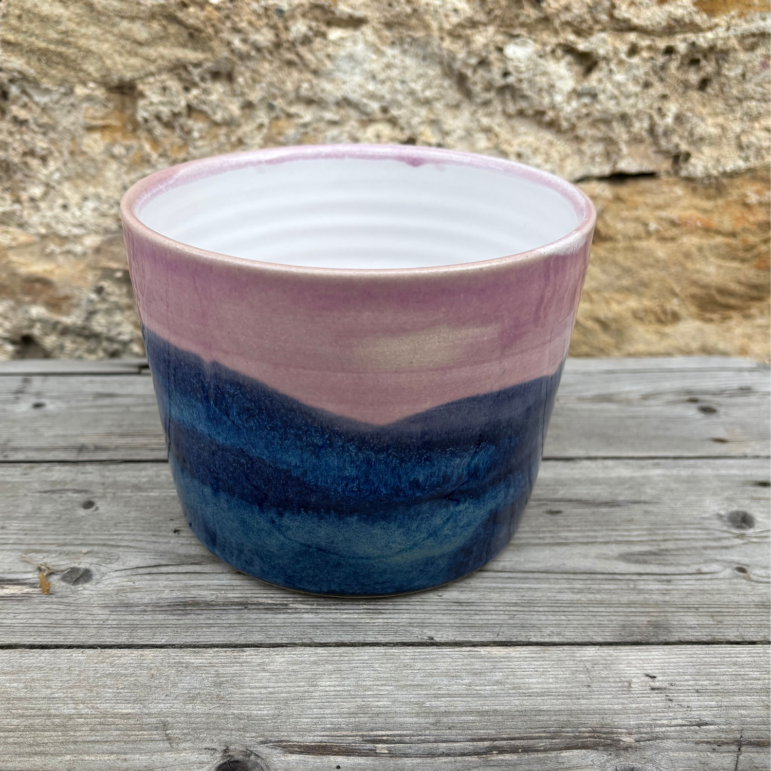 Ceramic pot with pink and blue gradient on a wooden surface
