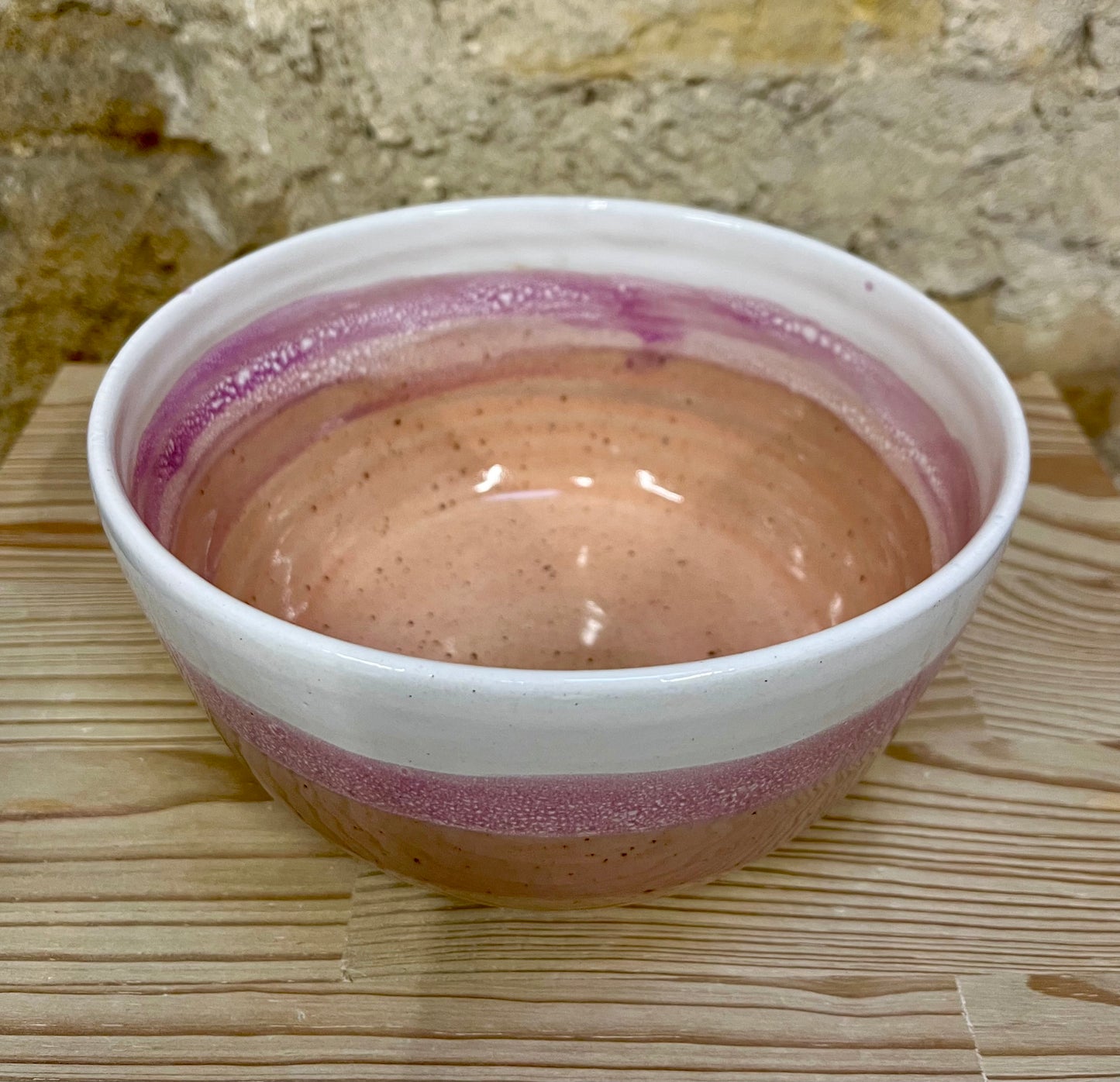 Ceramic bowl with pink interior and exterior on a wooden surface