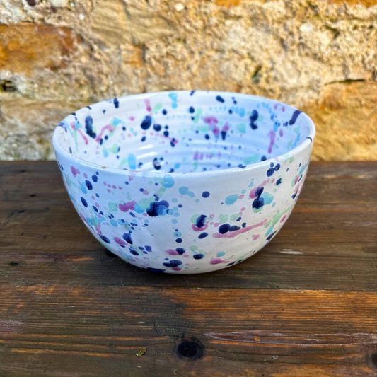 Speckled ceramic bowl on a wooden surface with a rustic background