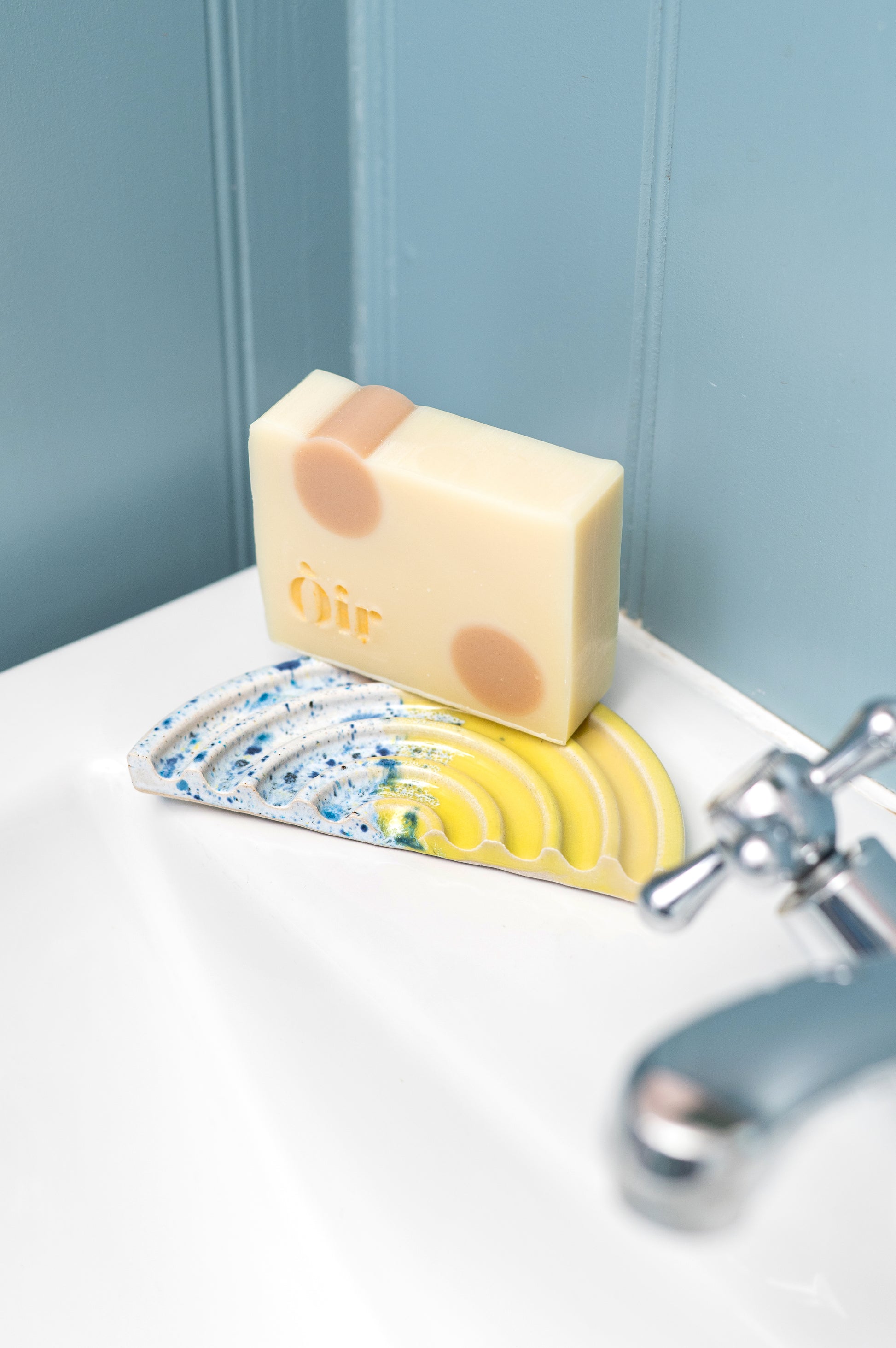 Bar of soap with a bear design on a soap dish next to a faucet in a bathroom.