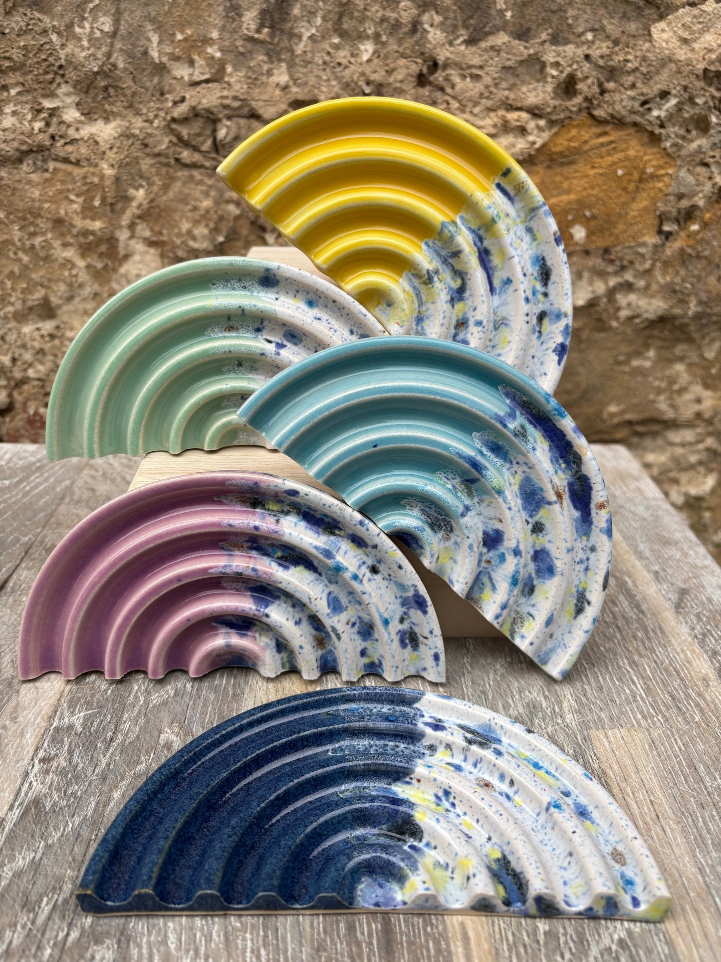 Set of colorful ceramic soap dishes on a stone surface