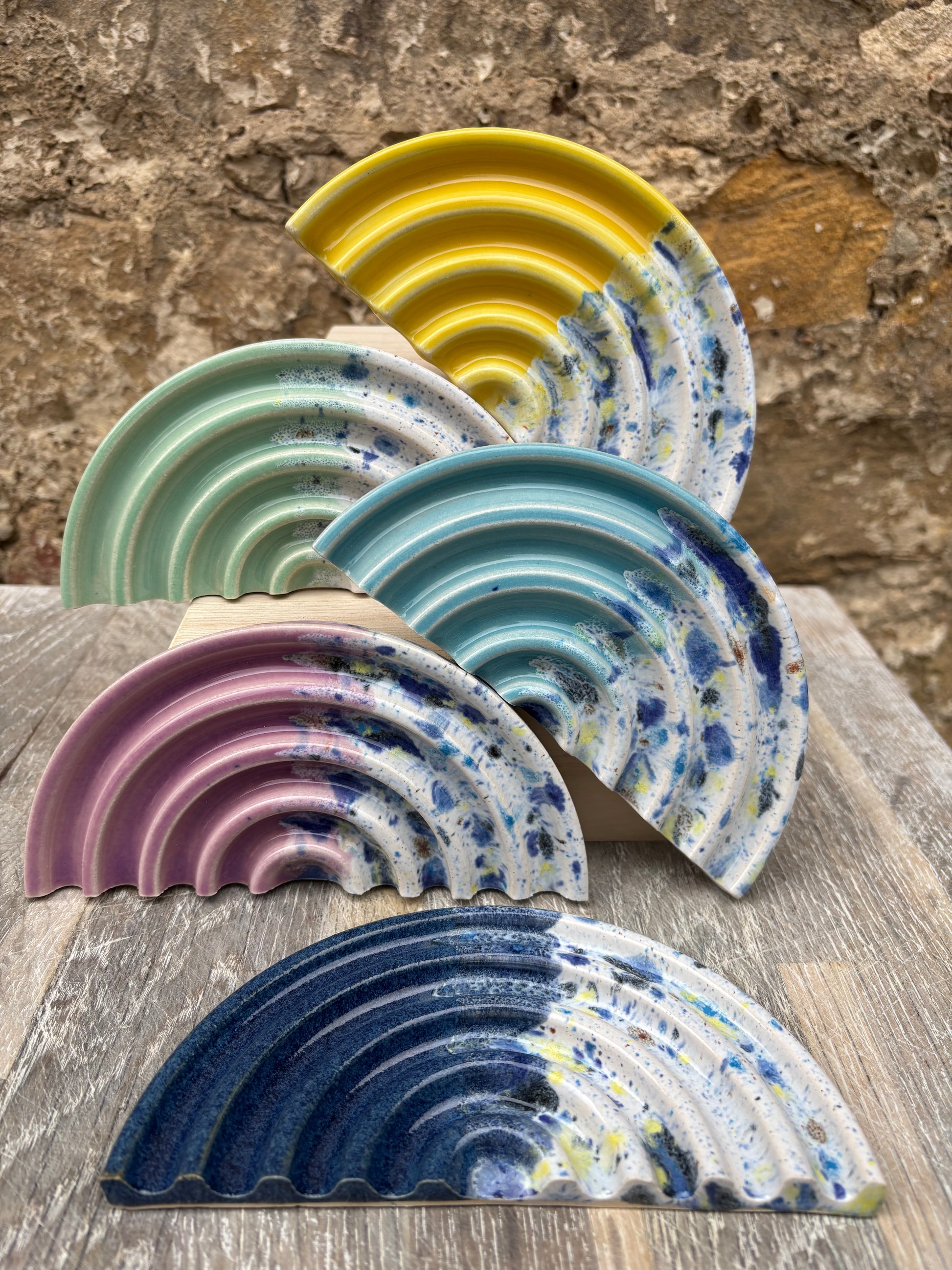 Set of colorful ceramic soap dishes on a stone surface