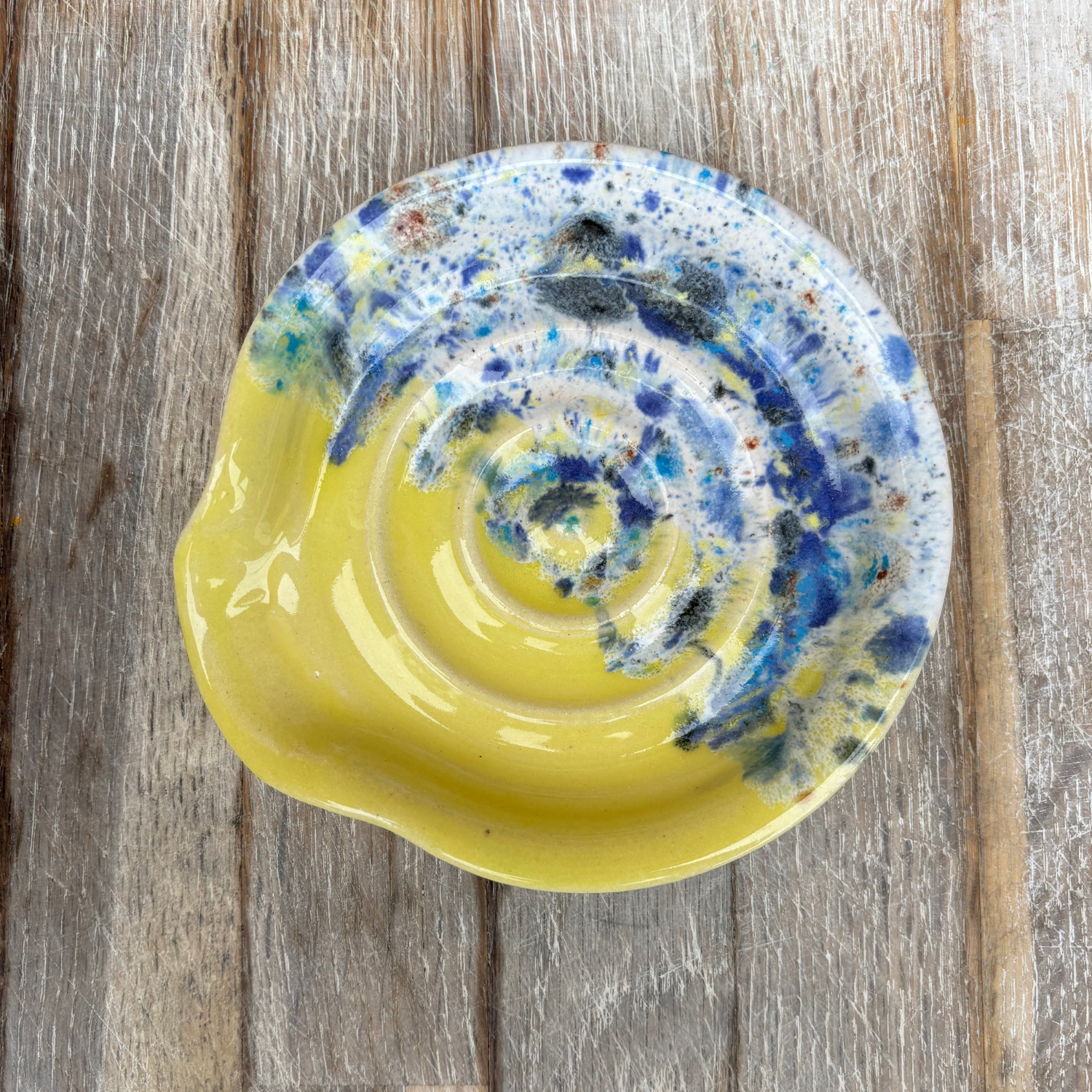Yellow ceramic plate with blue and white abstract design on a wooden surface