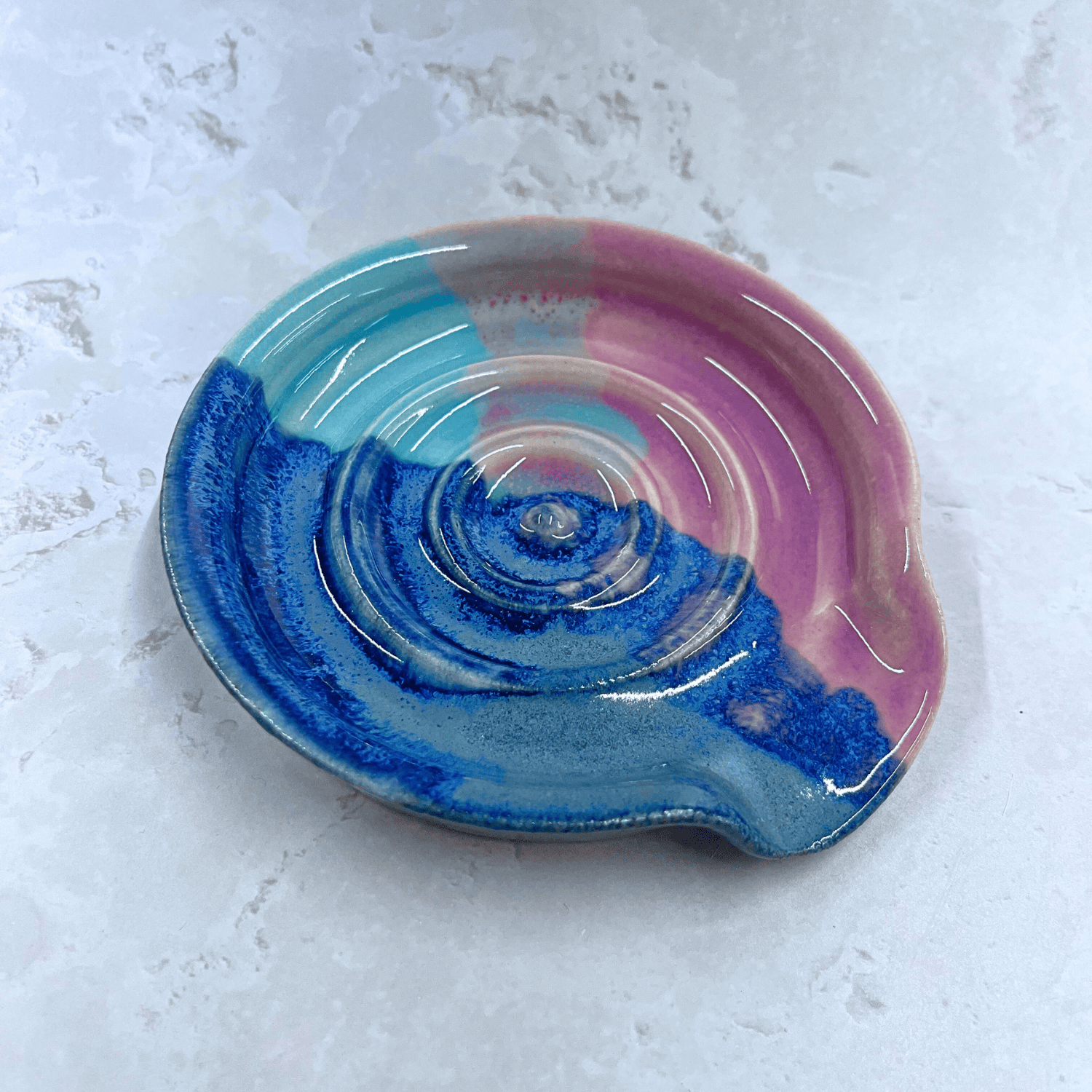 Ella Fletcher Designs Handmade UK Ceramic Spoon Rest in Scottish Sunrise Landscape design, circular spoon rest with raised edges in pink and blue layers inspired by the Scottish Sunrise