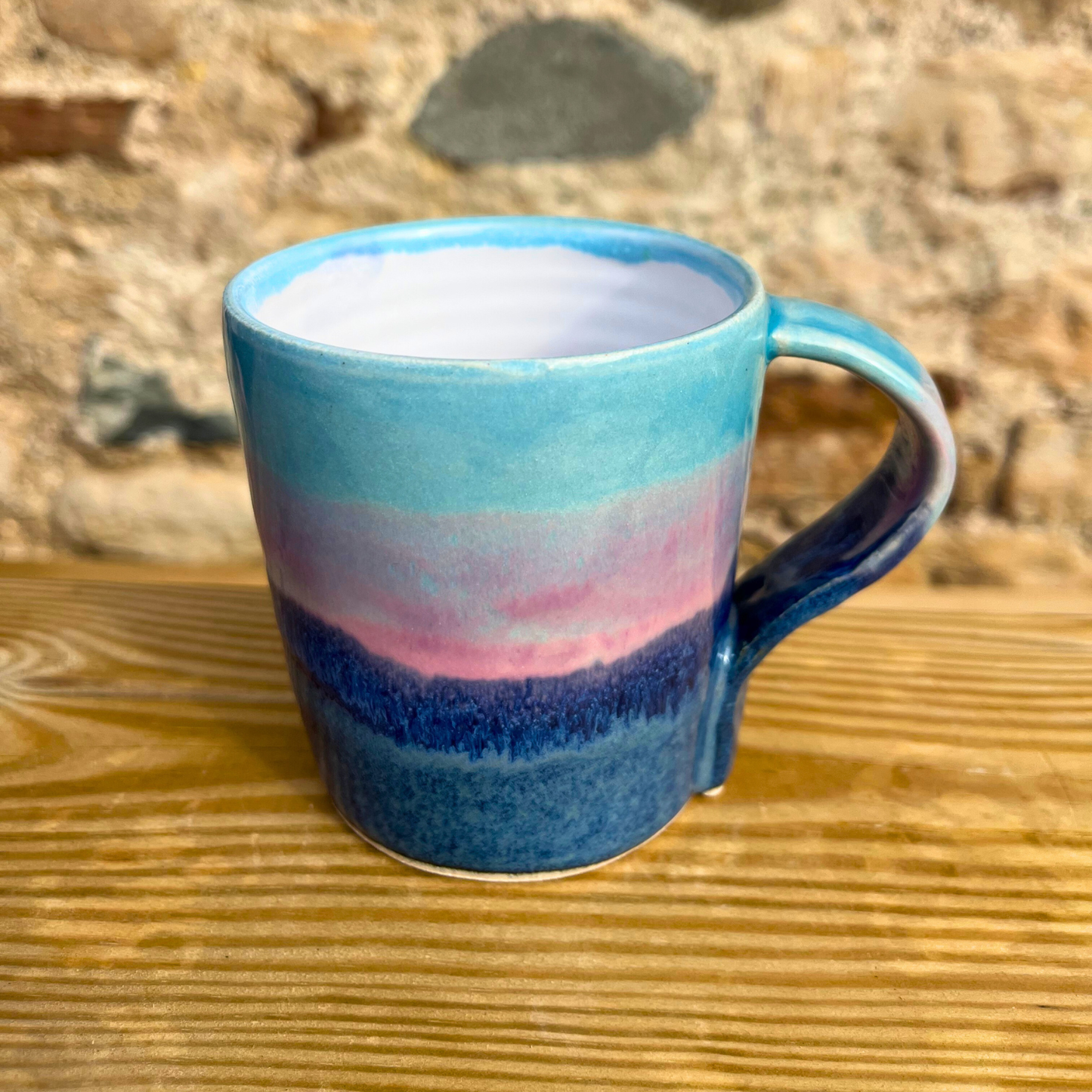 Blue ceramic mug with a gradient design on a wooden surface
