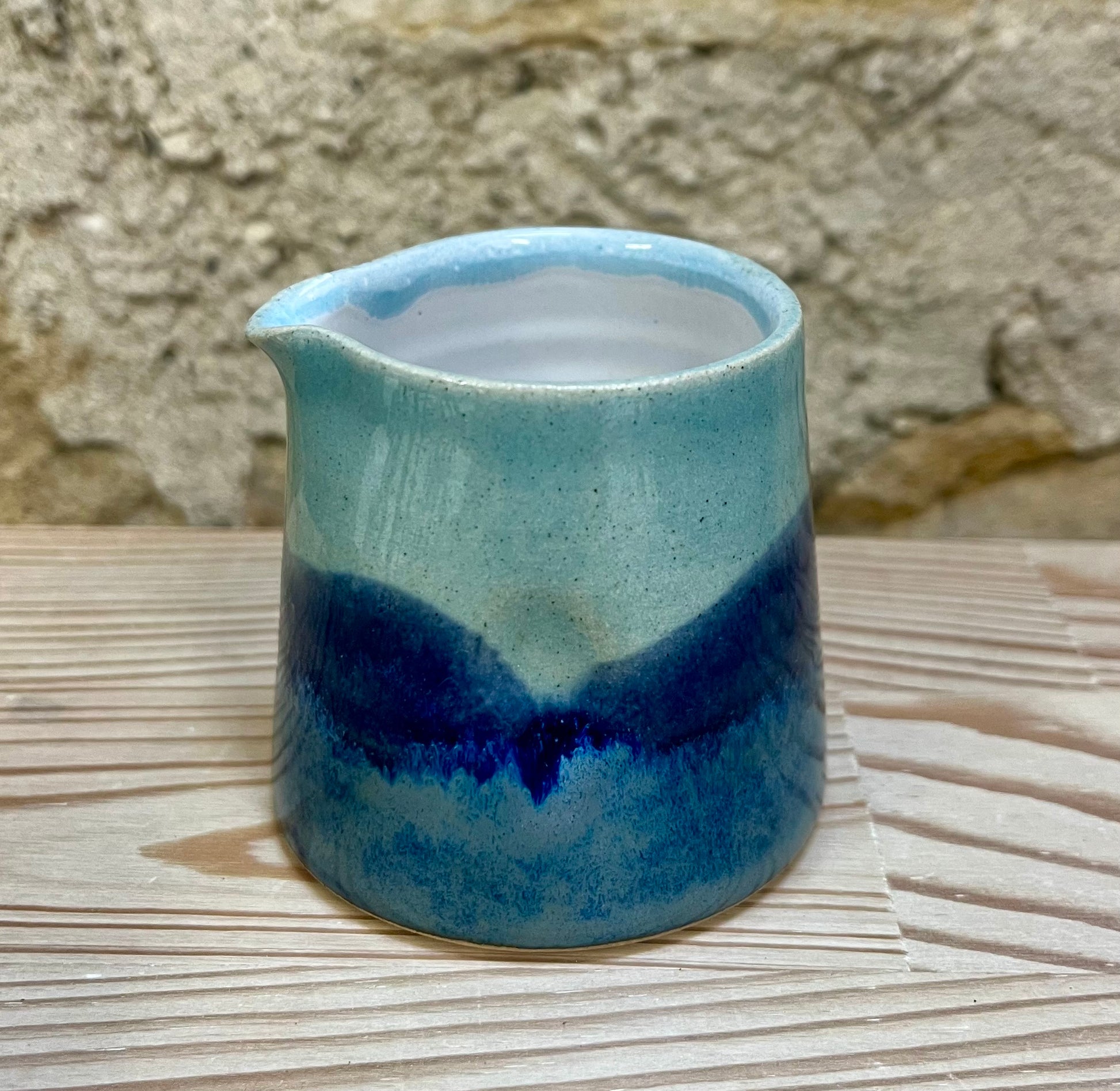Ceramic pitcher with blue glaze on a stone surface