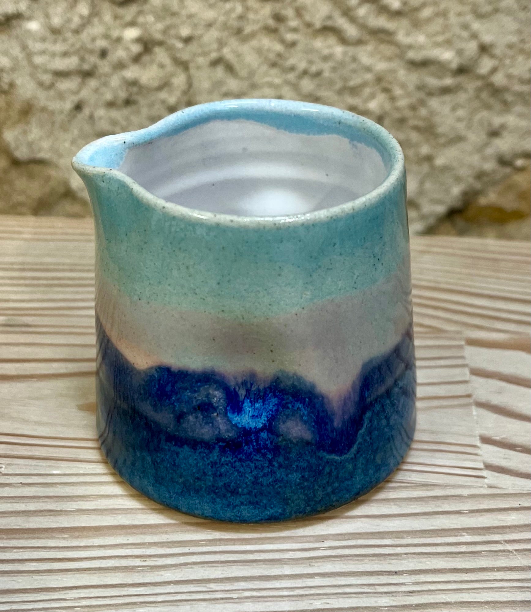 Ceramic pitcher with blue and white glaze on a woven surface