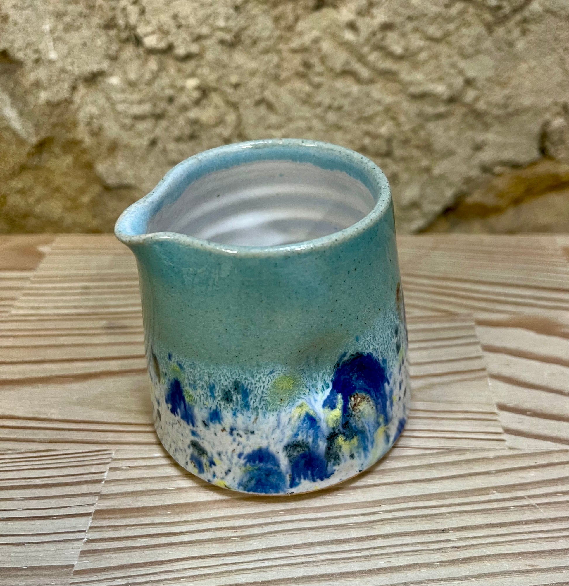 Ceramic pitcher with blue and white speckled design on a wooden surface.