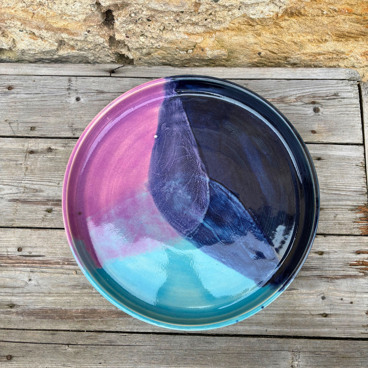 Multicolored ceramic tray on a wooden surface with a stone background
