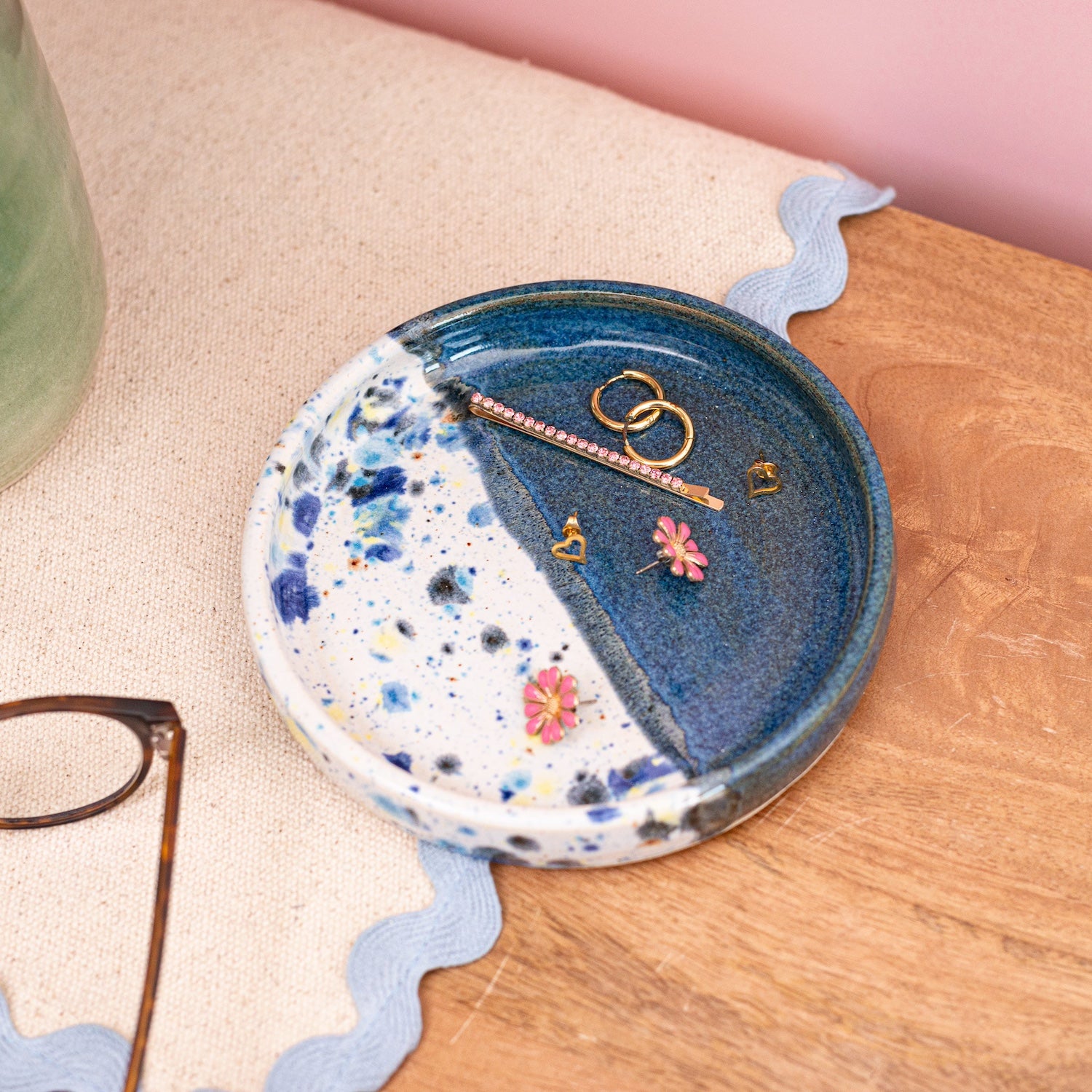 Ella Fletcher Designs Handmade Ceramic Trinket Dish in Navy Shoreline Design, small round dish with pink and multicolour speckles, featured with jewellery on a bedside table