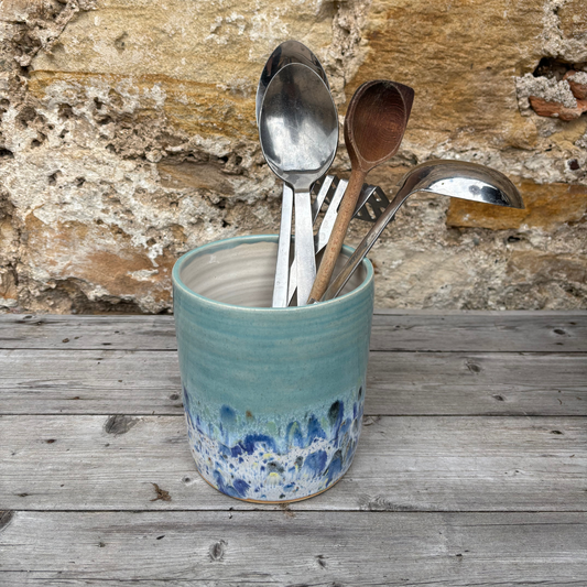 Ceramic container with spoons against a stone wall