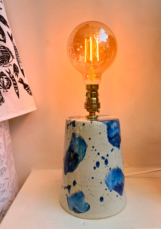 Ceramic lamp with blue speckles on a white surface