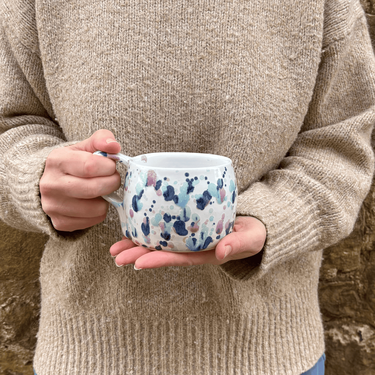 Ella Fletcher Designs Handmade Ceramics Large Round Mug in Sweepea design, mug being held featuring splashes of blues, pinks and green